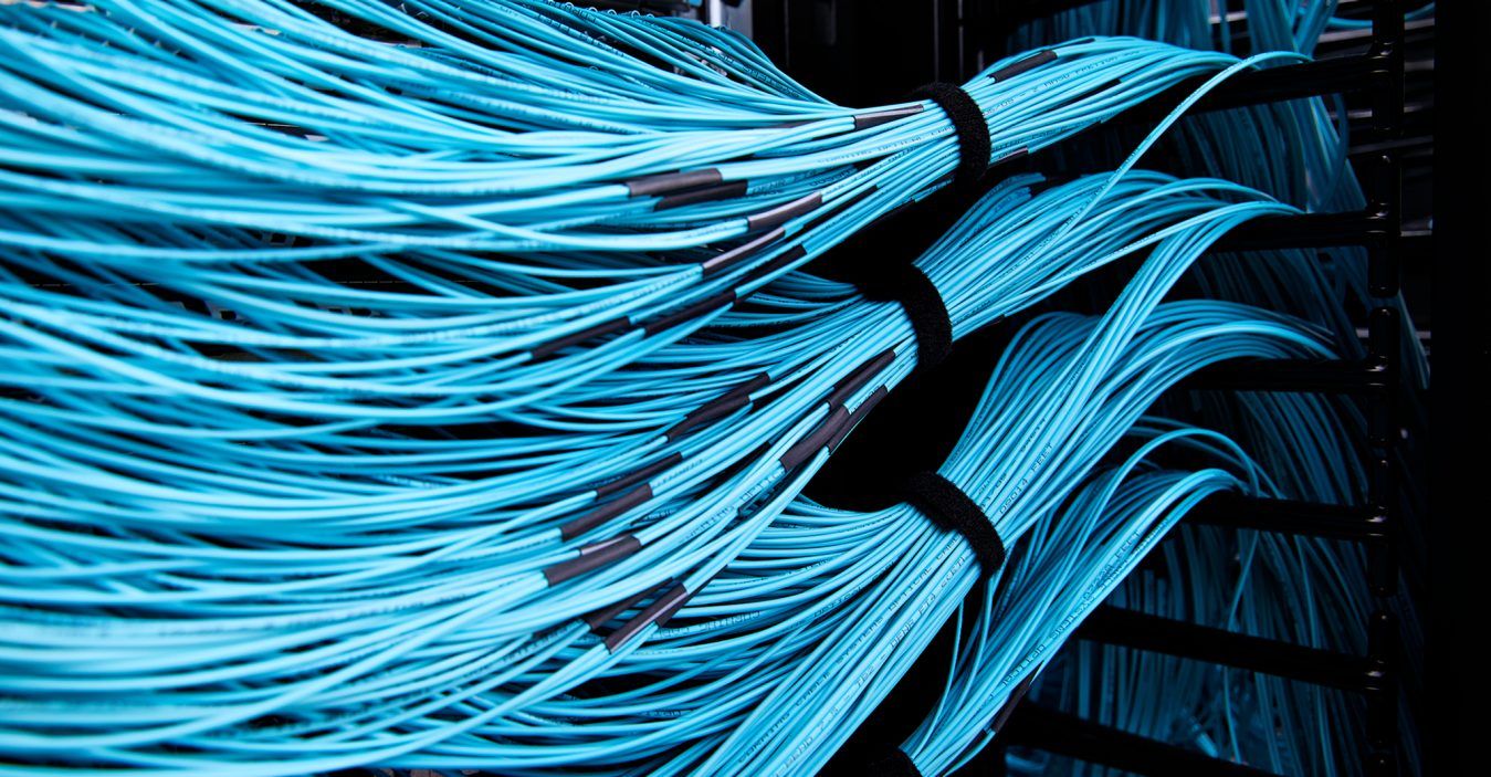 Svazek rozzářených optických vláken před serverovými racky AI datacentra